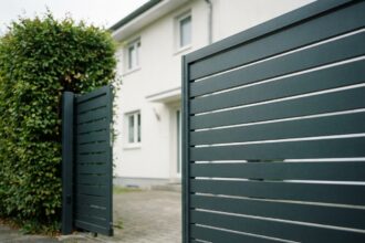 Portail coulissant en aluminium anthracite devant une entrée de maison étroite avec allée pavée