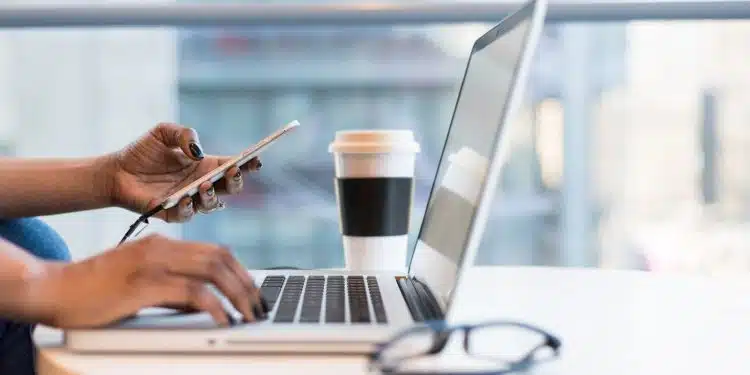 person using smartphone and MacBook